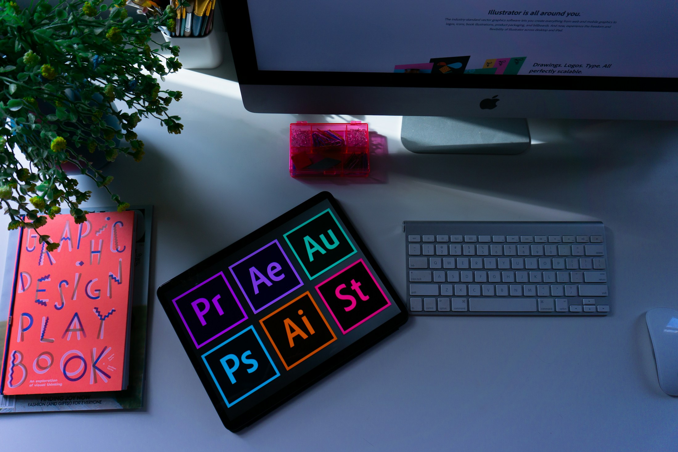 Fotografía de un escritorio creativo con monitor y herramientas de diseño Adobe
